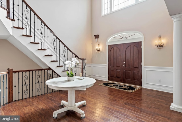 entryway featuring dark hardwood / wood-style floors, ornate columns, and a high ceiling