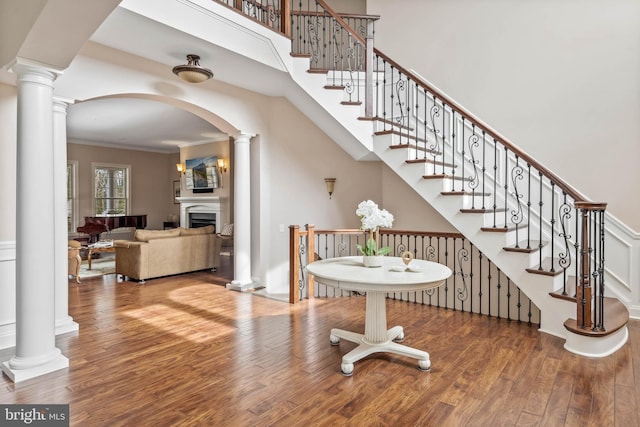 stairs with ornamental molding, ornate columns, and dark hardwood / wood-style flooring