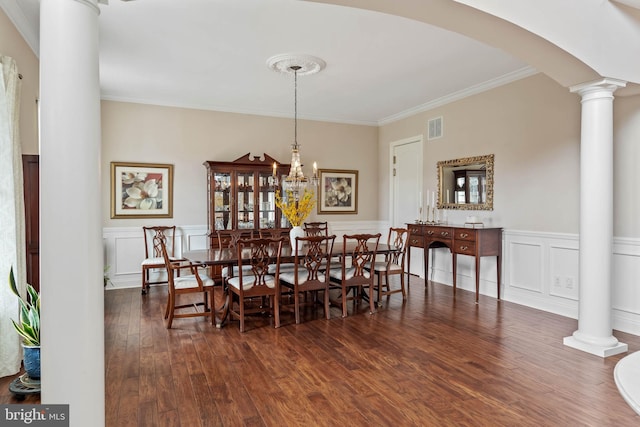 dining area with dark hardwood / wood-style flooring, crown molding, a chandelier, and decorative columns