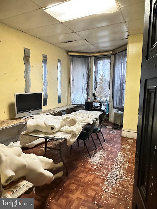 miscellaneous room featuring radiator heating unit and a drop ceiling