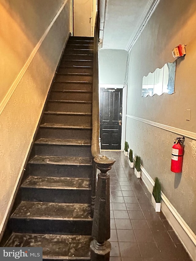 stairs with dark tile floors and crown molding