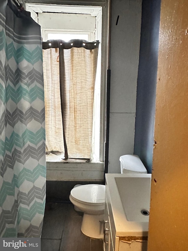 bathroom featuring toilet, vanity, and tile flooring