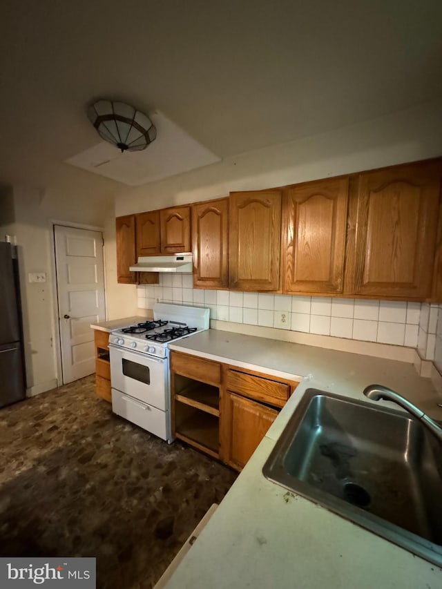 kitchen with stainless steel fridge, sink, white gas range oven, and tasteful backsplash