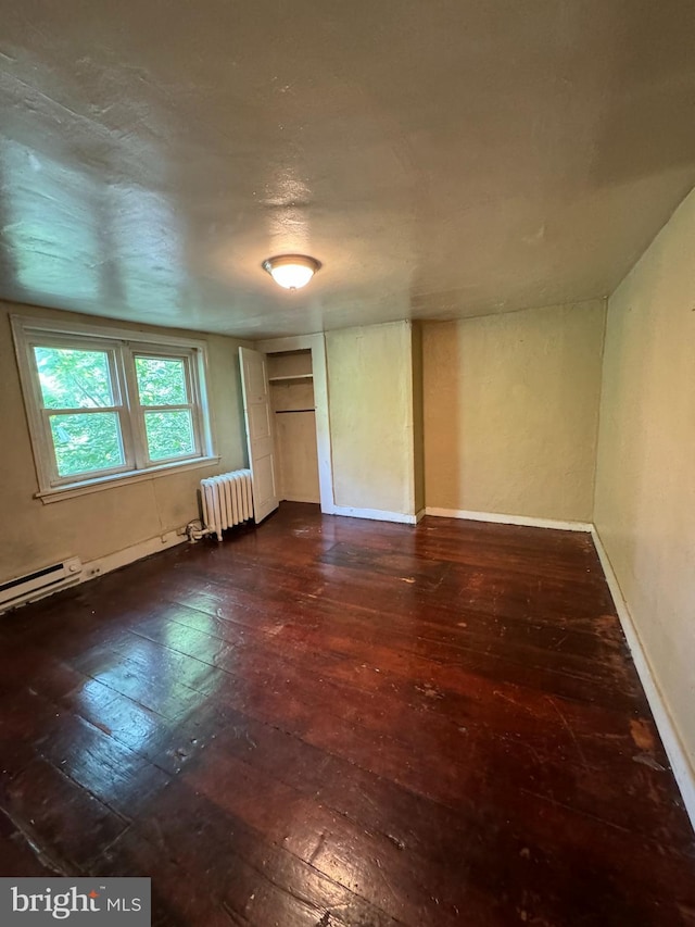 unfurnished room with baseboard heating, radiator heating unit, dark wood-type flooring, and a textured ceiling