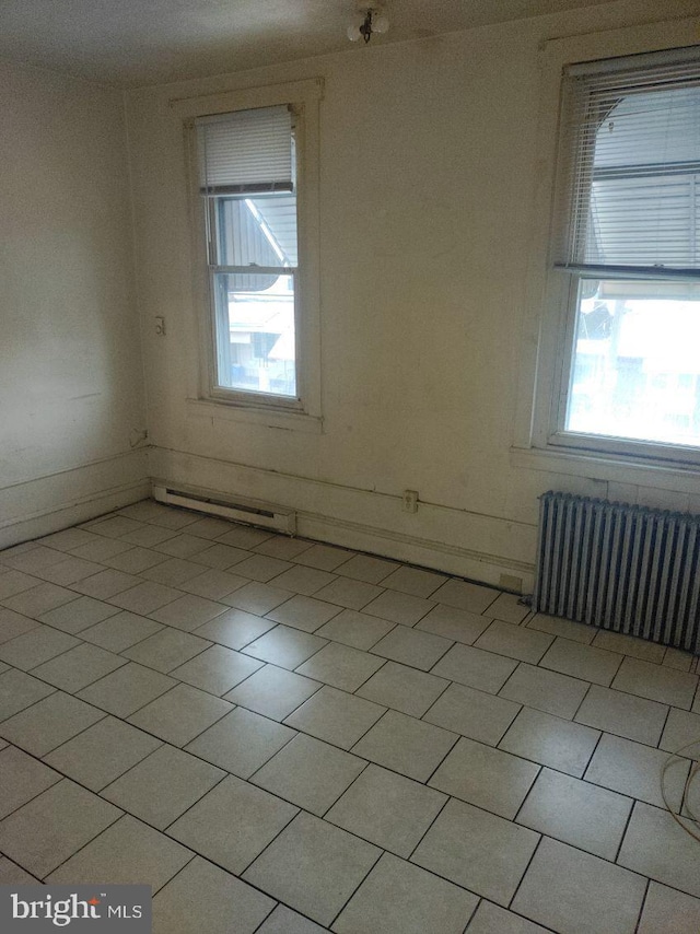 tiled spare room featuring plenty of natural light and radiator