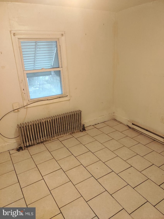 spare room with radiator heating unit and light tile floors