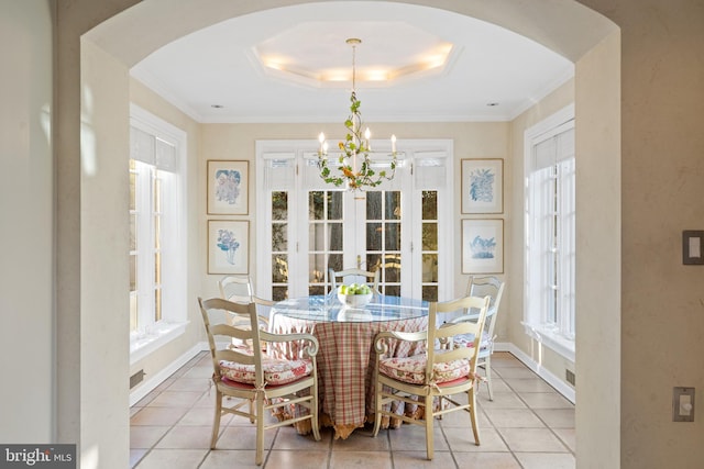 dining area with an inviting chandelier, a wealth of natural light, and a tray ceiling