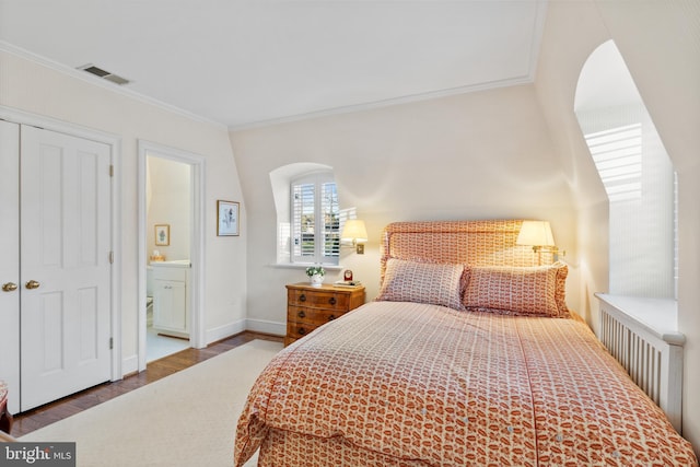 bedroom with dark hardwood / wood-style flooring, connected bathroom, and ornamental molding