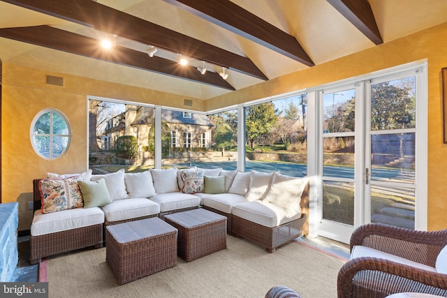 sunroom featuring plenty of natural light, rail lighting, and lofted ceiling with beams