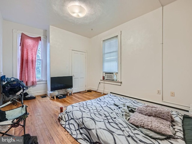 bedroom with hardwood / wood-style flooring, cooling unit, and a textured ceiling