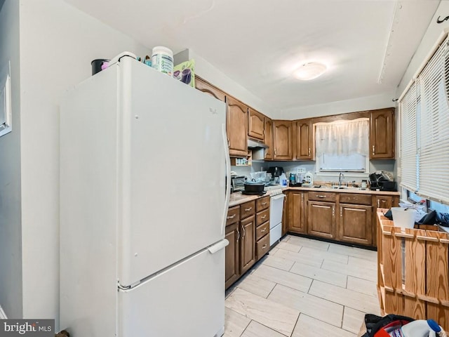 kitchen featuring light tile patterned floors, white refrigerator, and sink