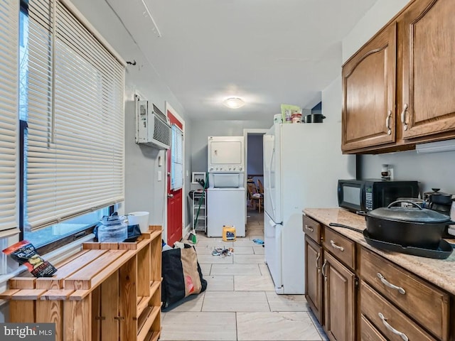 kitchen featuring light stone countertops, white refrigerator, a wall unit AC, light tile patterned floors, and stacked washer and clothes dryer