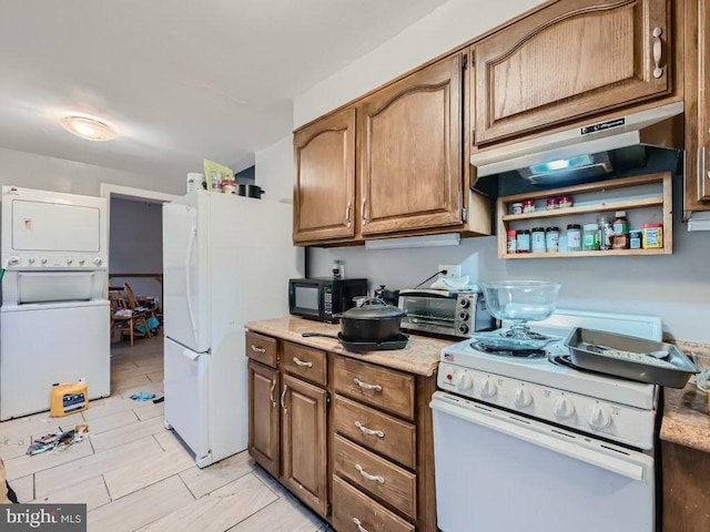 kitchen with stacked washer / drying machine, exhaust hood, and white appliances