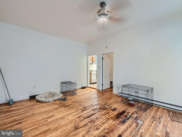 interior space with light wood-type flooring, baseboard heating, and ceiling fan