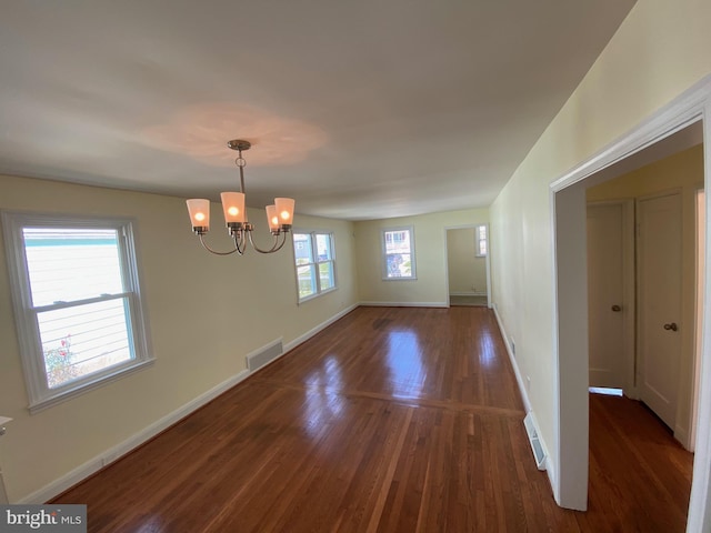 empty room with an inviting chandelier and dark wood-type flooring