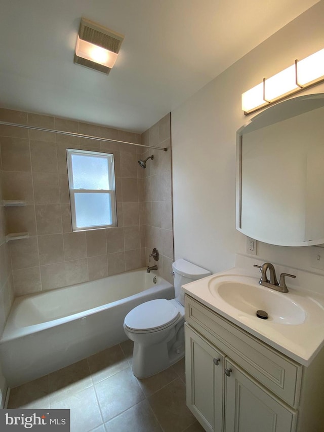 full bathroom with tile floors, toilet, large vanity, and tiled shower / bath