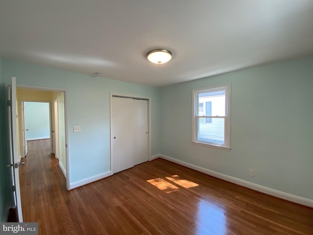 unfurnished bedroom featuring a closet and dark wood-type flooring