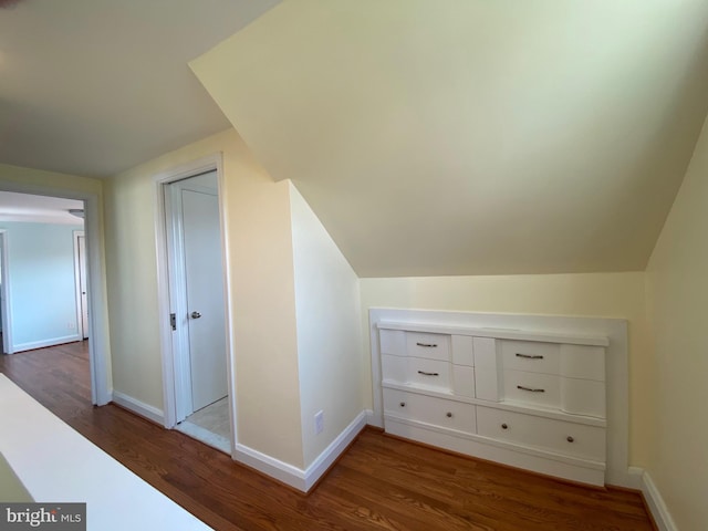 additional living space featuring vaulted ceiling and dark hardwood / wood-style flooring