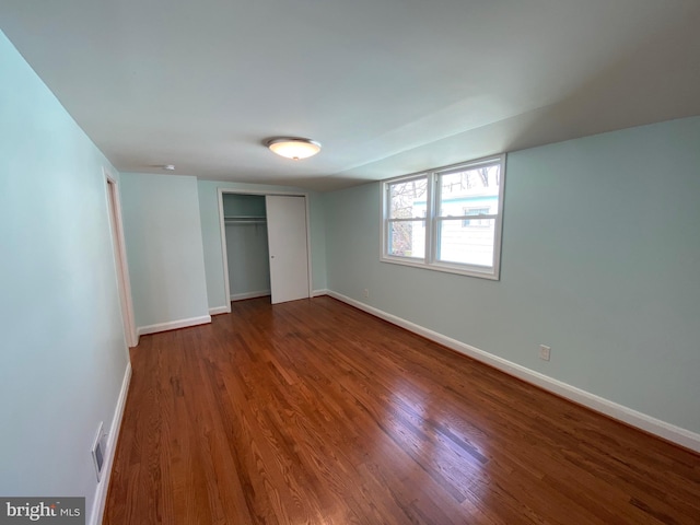 unfurnished bedroom featuring a closet and dark hardwood / wood-style flooring