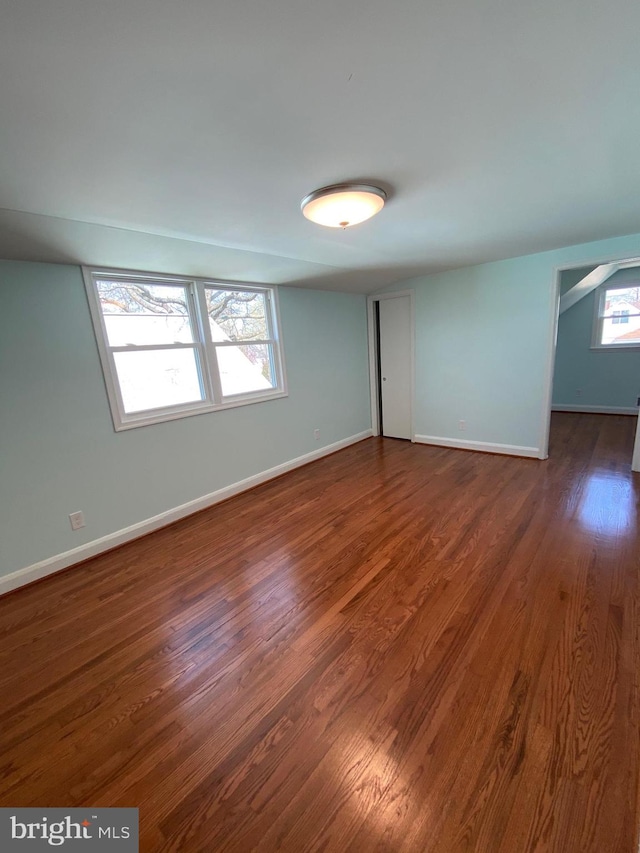 empty room featuring a wealth of natural light and dark hardwood / wood-style flooring