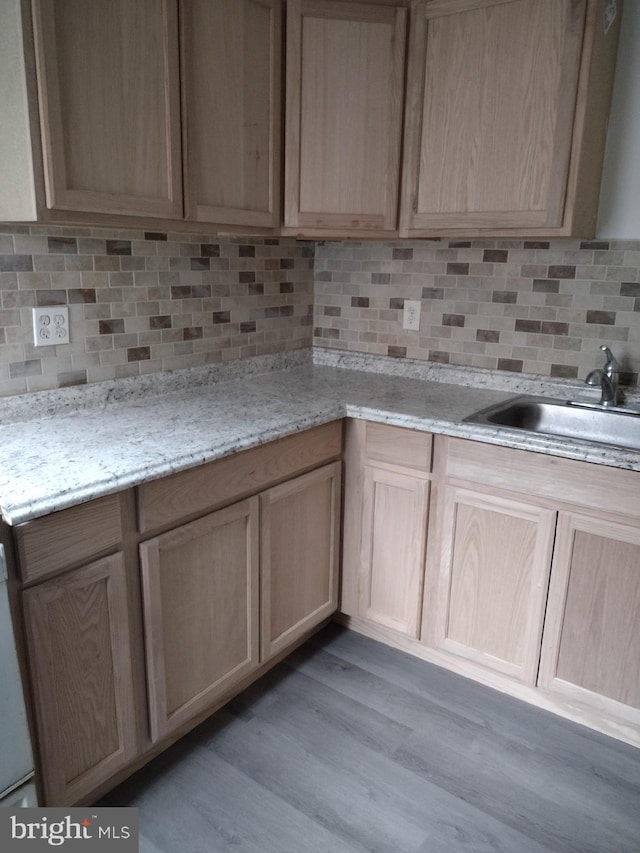 kitchen with light stone countertops, backsplash, light hardwood / wood-style floors, and light brown cabinetry