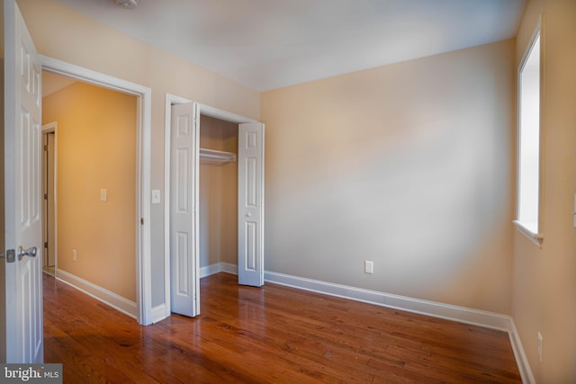 unfurnished bedroom with a closet and dark hardwood / wood-style floors