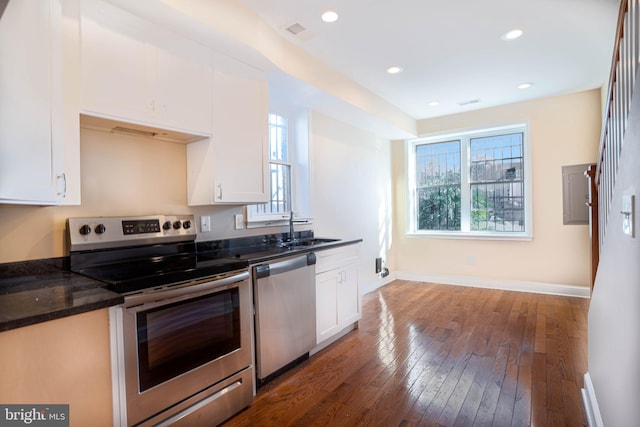 kitchen with sink, dark hardwood / wood-style flooring, dark stone countertops, appliances with stainless steel finishes, and white cabinetry