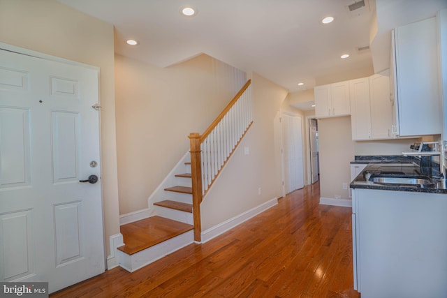 kitchen featuring white cabinets, dark stone counters, sink, and light hardwood / wood-style floors