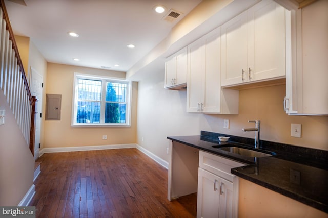 kitchen featuring dark hardwood / wood-style flooring, sink, dark stone countertops, and white cabinetry