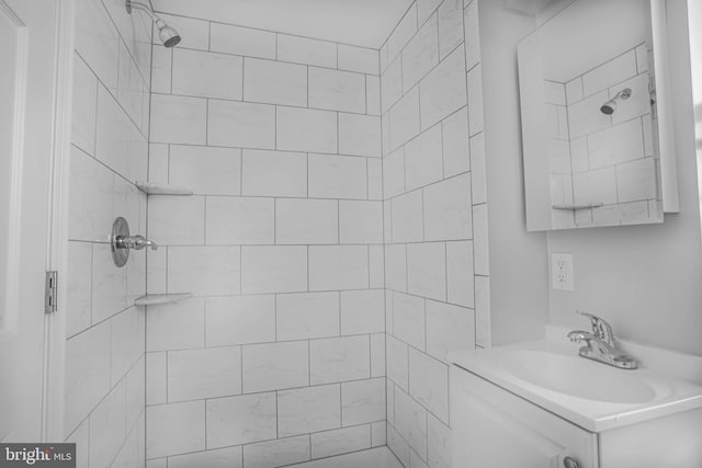 bathroom with tiled shower and large vanity