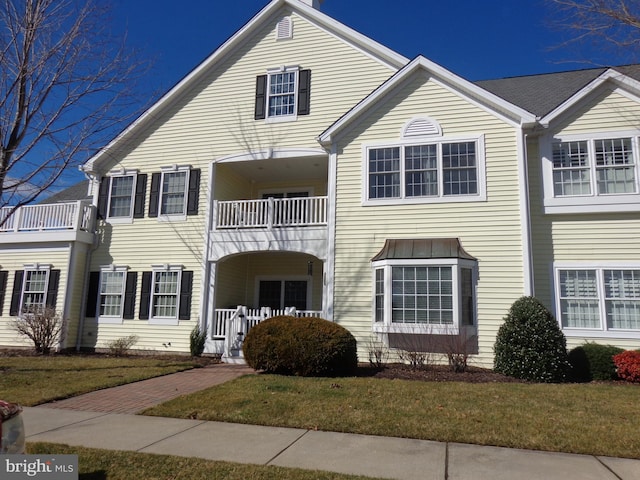 view of front of property featuring a balcony and a front yard