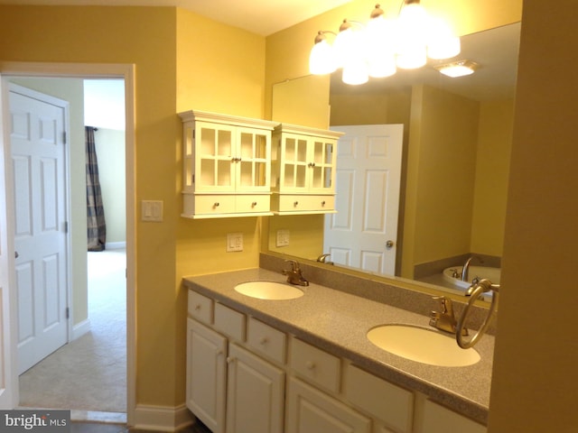 bathroom featuring a chandelier, dual bowl vanity, and a bath