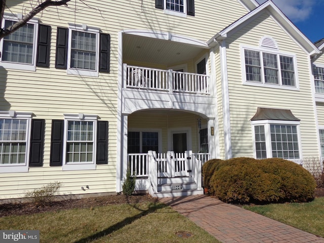 multi unit property with a balcony and a front yard