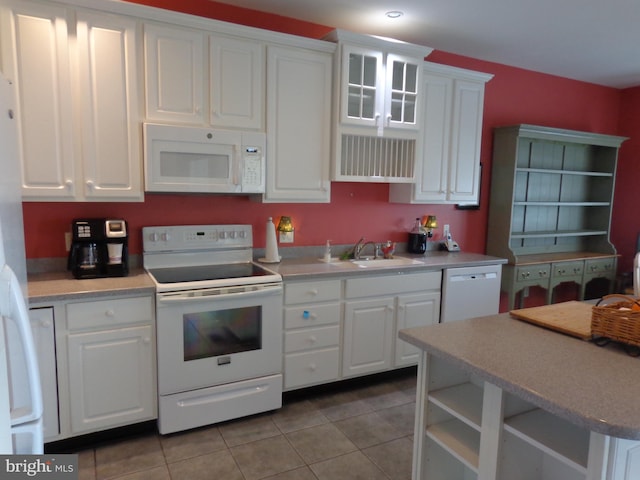 kitchen featuring white appliances, light tile flooring, white cabinets, and sink