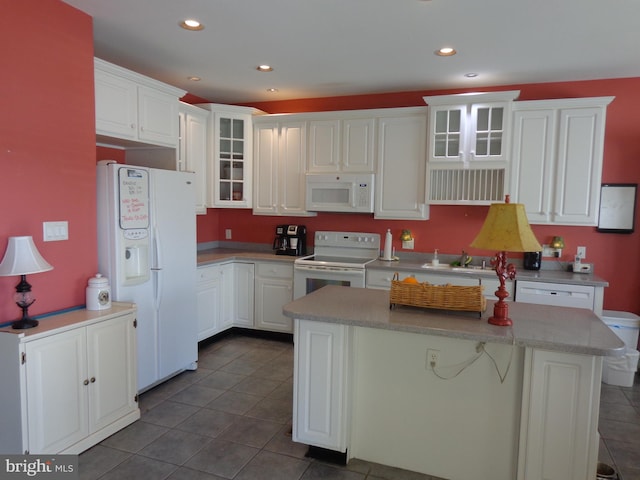 kitchen with sink, white appliances, dark tile floors, and white cabinets