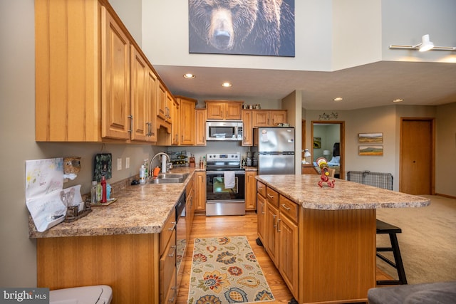 kitchen featuring sink, a breakfast bar area, stainless steel appliances, light carpet, and a center island