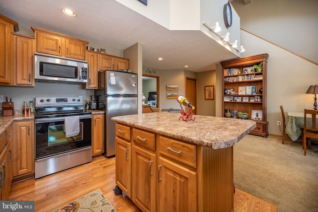 kitchen with light carpet, a kitchen island, and appliances with stainless steel finishes