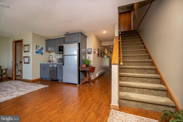 stairway featuring a baseboard heating unit, dark wood-type flooring, and sink