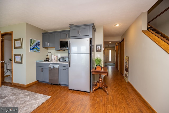 kitchen featuring light hardwood / wood-style floors, gray cabinets, stainless steel appliances, and sink