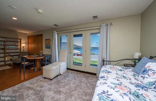 carpeted bedroom featuring a water view and access to outside