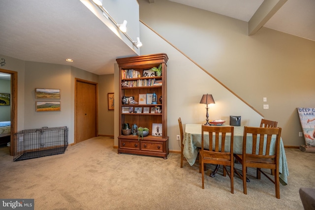 dining space featuring beam ceiling and light colored carpet