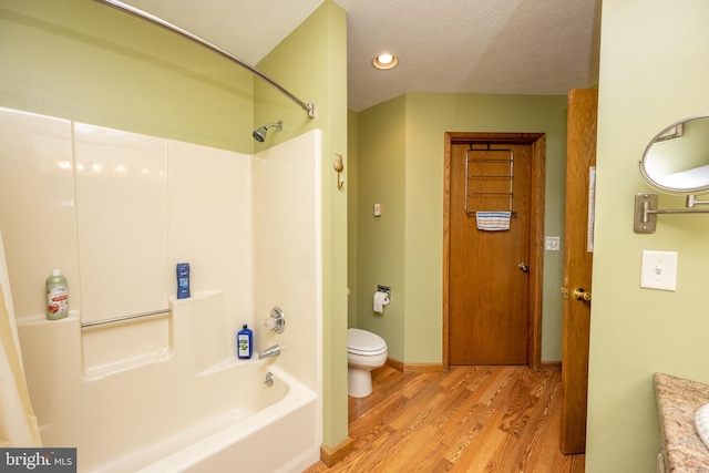 full bathroom featuring toilet, vanity, a textured ceiling, shower / bathtub combination, and hardwood / wood-style floors