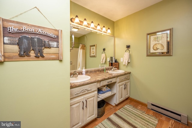 bathroom featuring double sink vanity, hardwood / wood-style flooring, and a baseboard heating unit