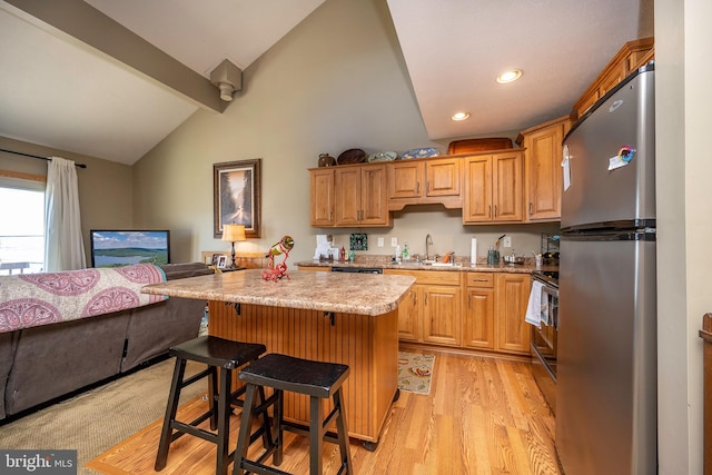 kitchen featuring appliances with stainless steel finishes, light stone counters, a breakfast bar, light hardwood / wood-style flooring, and lofted ceiling with beams