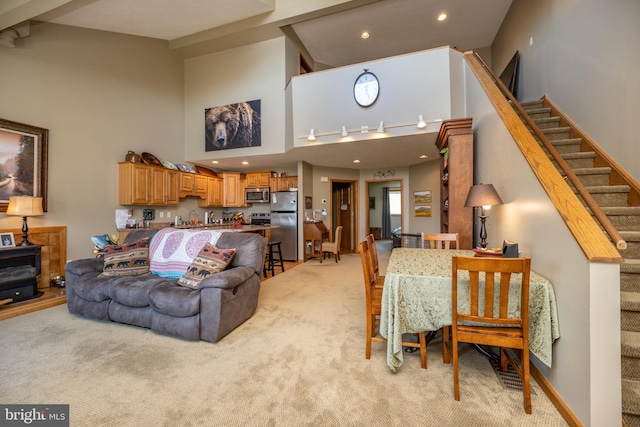 living room featuring light carpet, a high ceiling, and beam ceiling