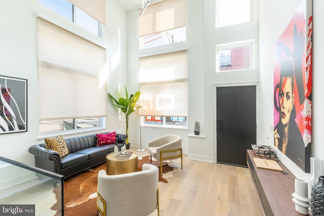 living room featuring light wood-type flooring and a towering ceiling