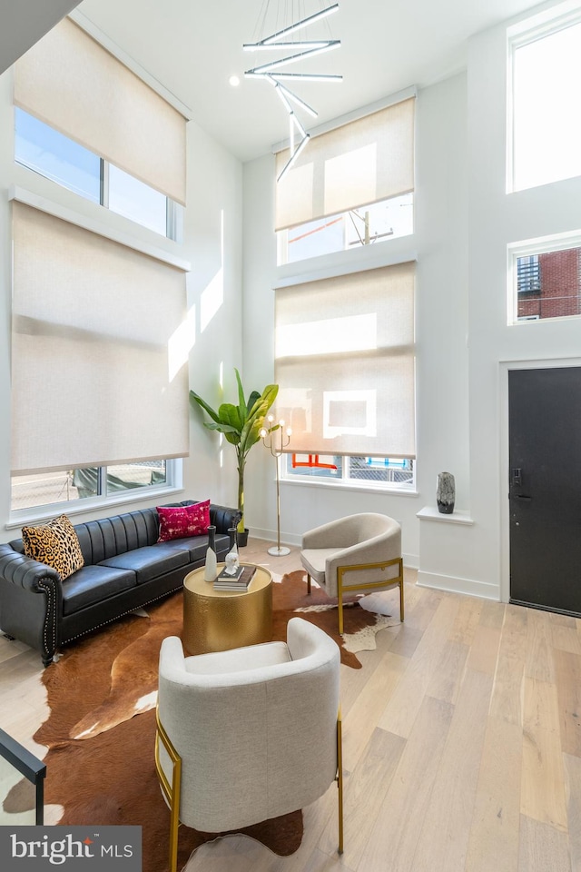 living room featuring a wealth of natural light, light wood-type flooring, and a towering ceiling