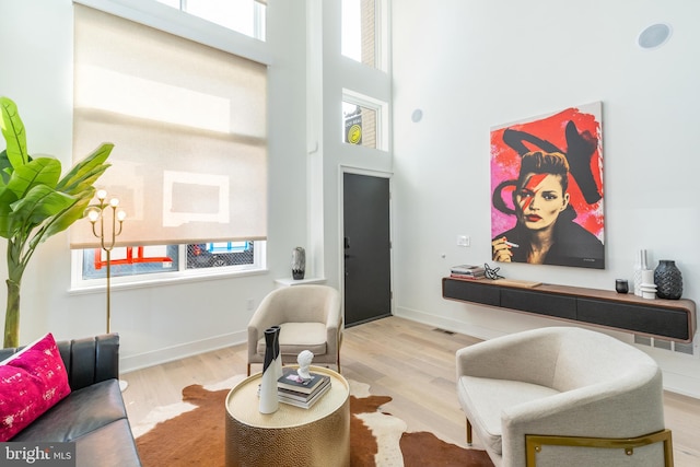 living room featuring light hardwood / wood-style flooring, a wealth of natural light, a high ceiling, and a chandelier