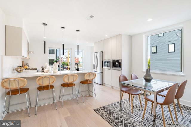 kitchen featuring white cabinets, light hardwood / wood-style flooring, stainless steel refrigerator with ice dispenser, and a wealth of natural light