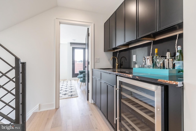 bar with beverage cooler, lofted ceiling, sink, and light wood-type flooring